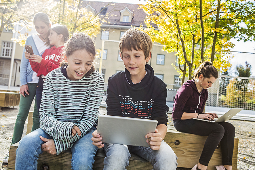 Les élèves utilisent les appareils mobiles dans la cour de l'école.