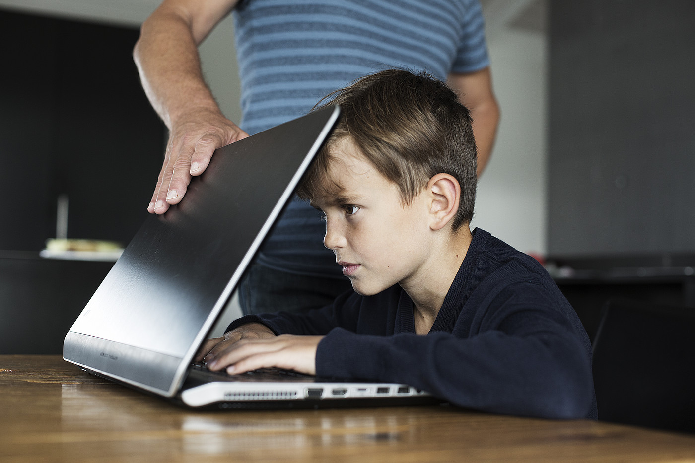 Un garçon est concentré sur l'écran et ne peut pas remettre l'ordinateur portable.