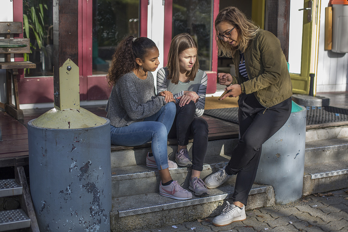 Une animatrice explique quelque chose aux enfants sur son smartphone.