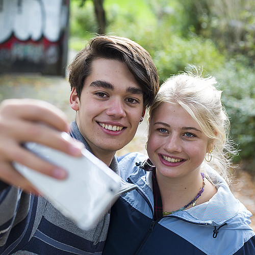 Un garçon et une fille prennent une photo ensemble avec leur portable. 