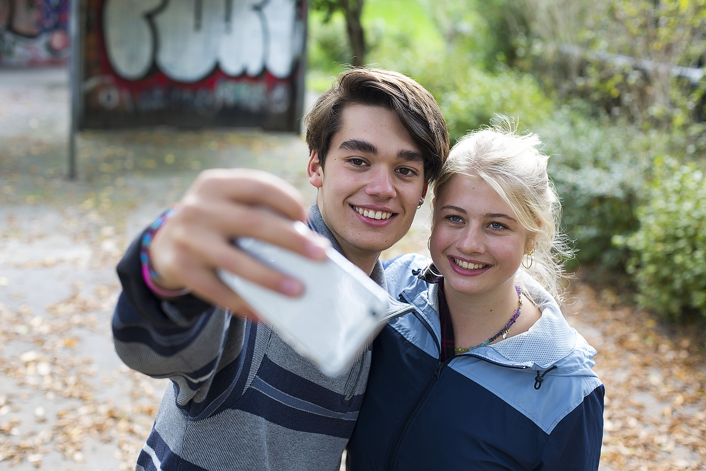 Un garçon et une fille prennent une photo ensemble avec leur portable. 