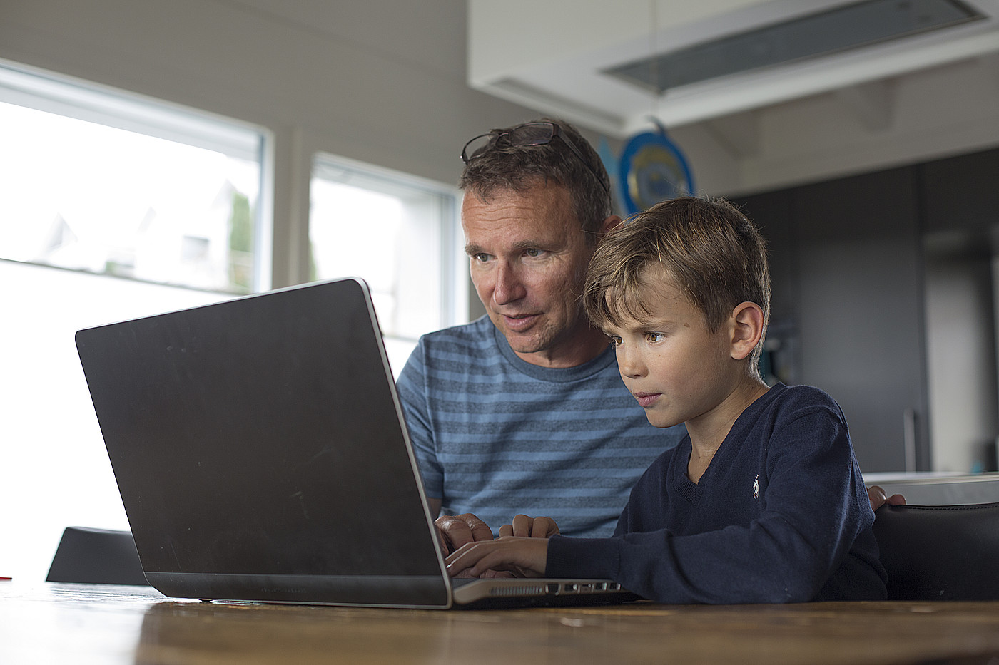 Un père et un enfant regardant ensemble un ordinateur portable.