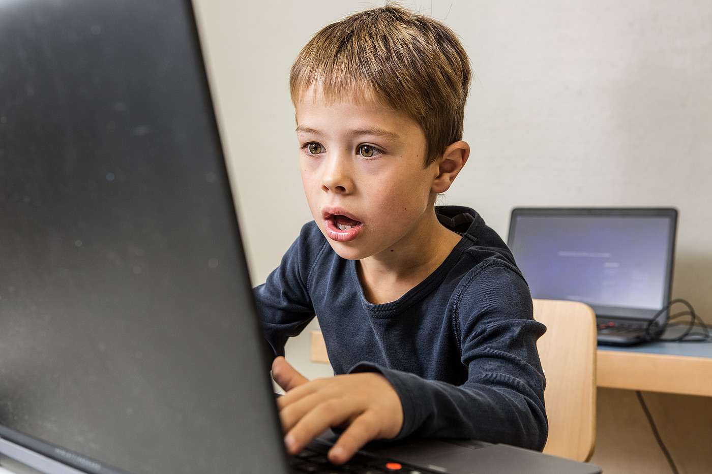 Un petit garçon voit quelque chose de menaçant sur l'ordinateur portable.