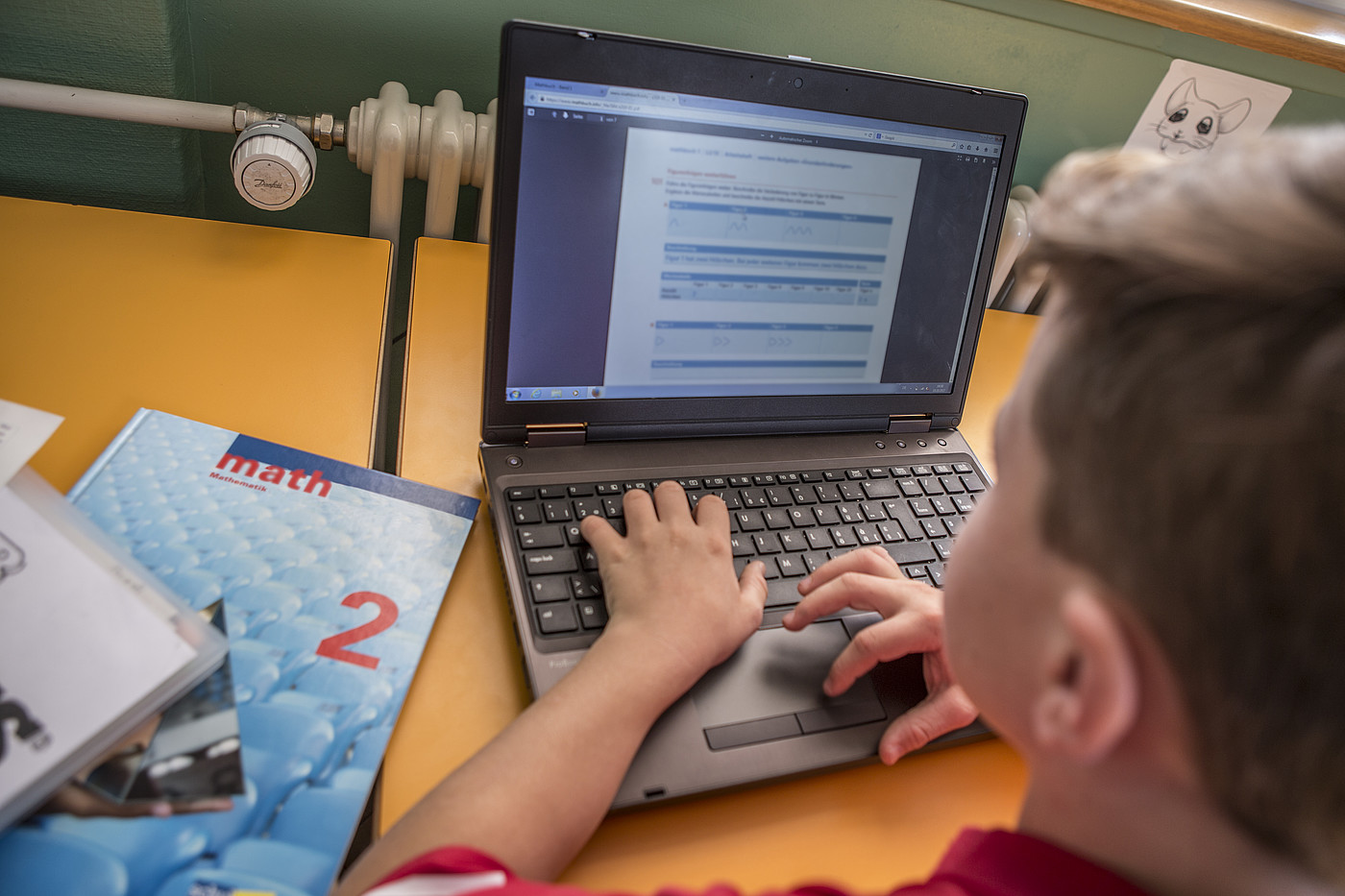 Un garçon est en train de résoudre des exercices de mathématiques sur son ordinateur portable.