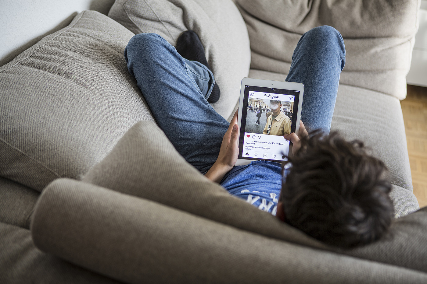 Un adolescent allongé sur le canapé, Instagram ouvert sur sa tablette.