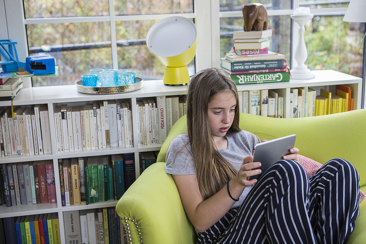 Un adolescent assis sur un canapé avec une tablette.