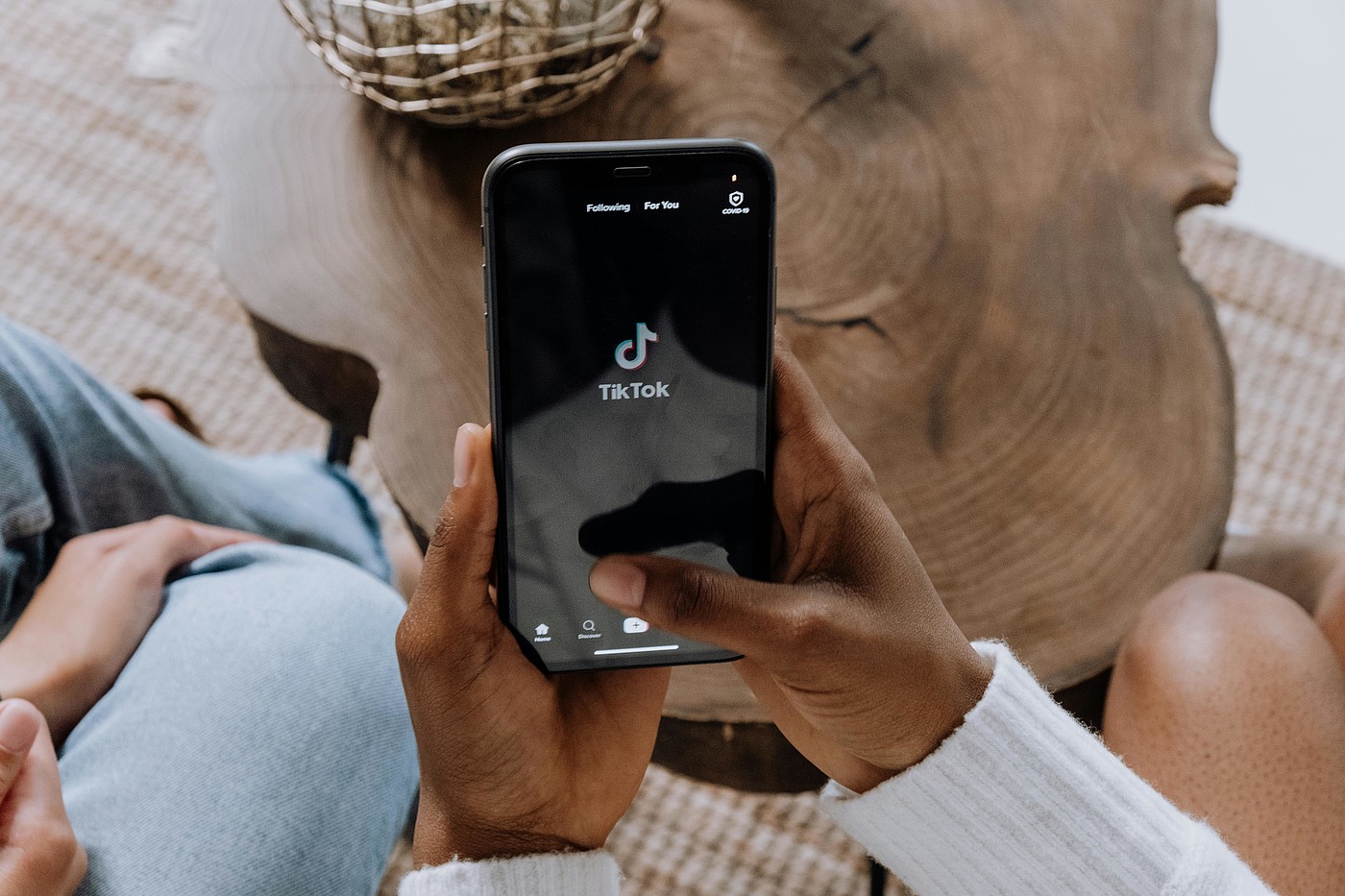 Deux personnes sont assises l'une à côté de l'autre, l'une d'elles tient un smartphone avec le logo TikTok dessus