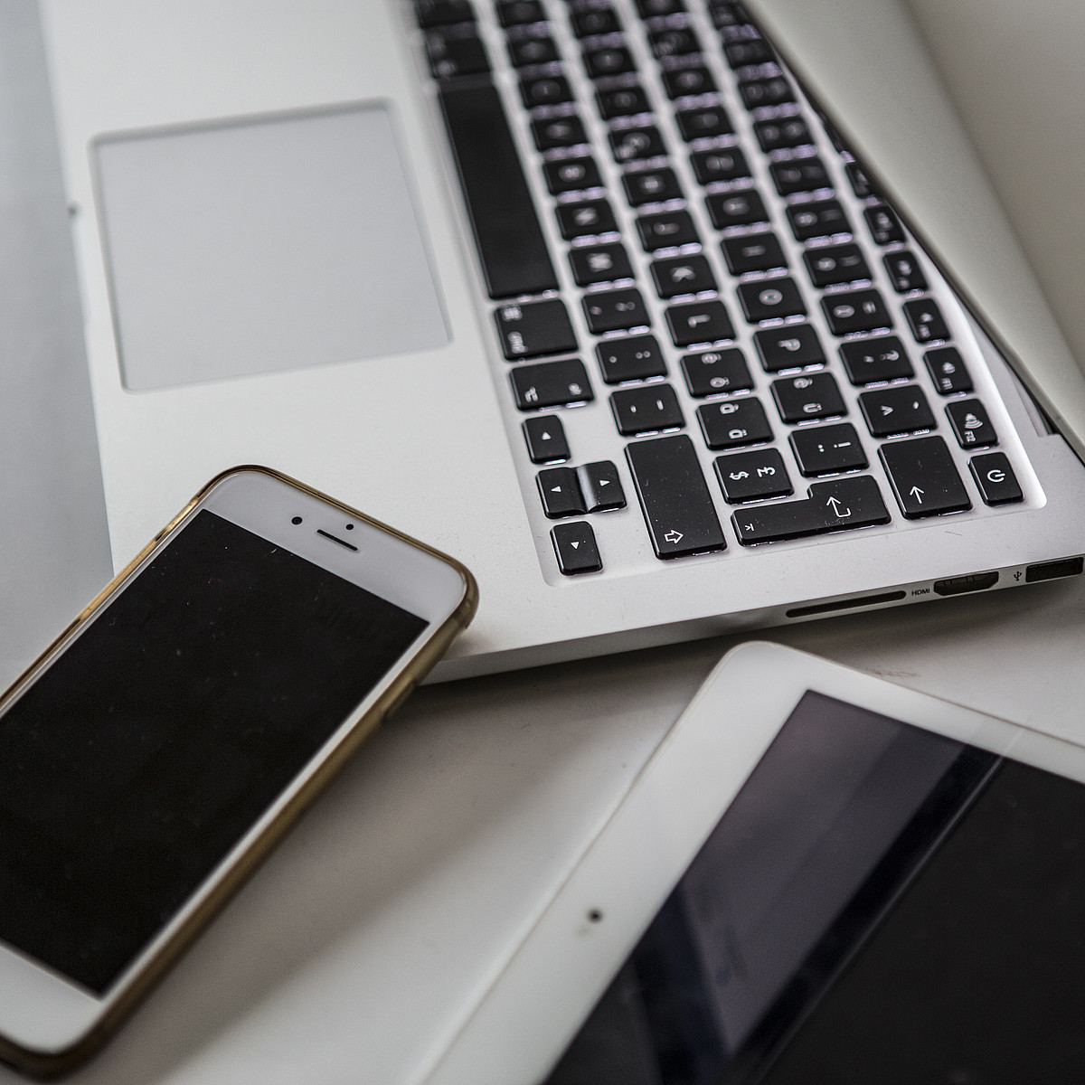 Un smartphone, une tablette et un ordinateur portable sont posés sur une table.
