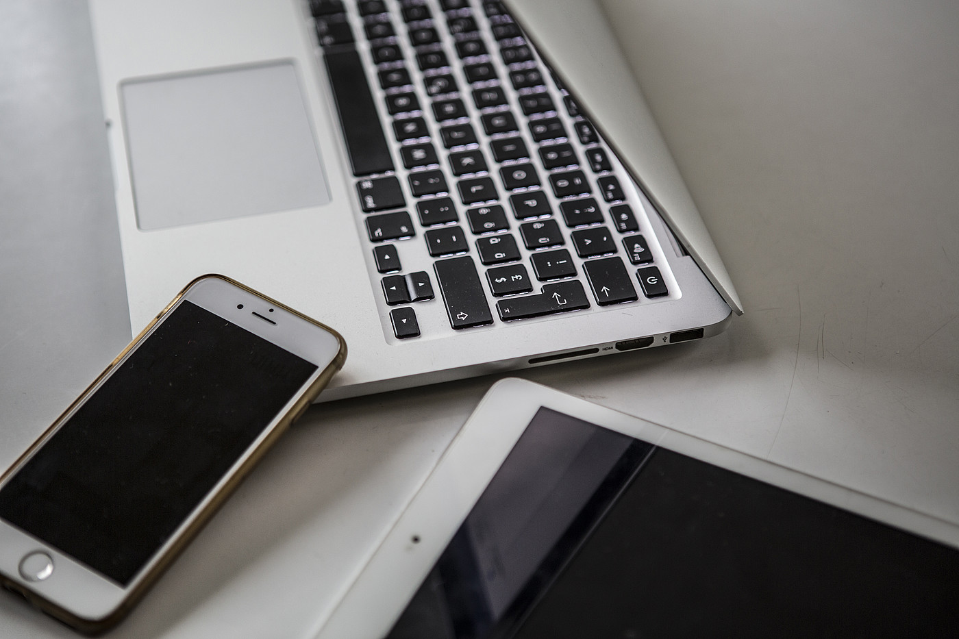 Un smartphone, une tablette et un ordinateur portable sont posés sur une table. 