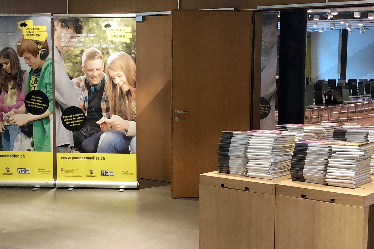 Une salle de réception vue de l'extérieur avec une pile de brochures sur la table à l'entrée.